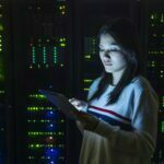 Young woman working on digital tablet in server room